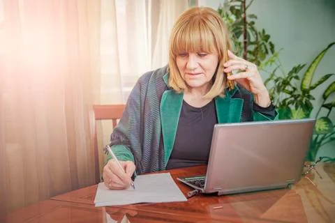 Elderly lady writing down orders, work from home Stock Photos