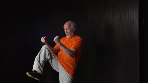 Elderly male athlete doing forward kick in motion Video stock 314502511