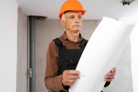 Elderly male builder studying layout plan new house, working with documents.. Stock Photos