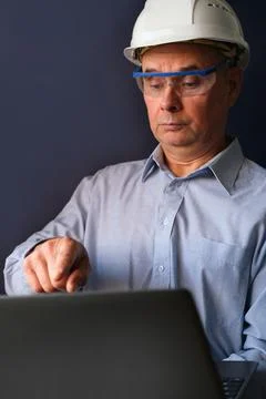 Elderly male engineer, builder in protective helmet, glasses looking seriousl Stock Photos