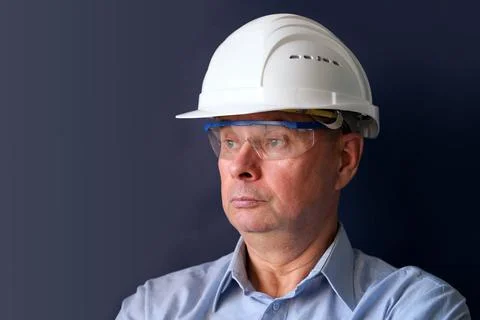 Elderly male engineer, builder in protective helmet, glasses looking seriousl Stock Photos
