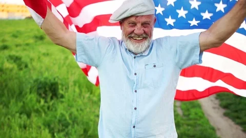Elderly man with the American flag on a background of green grass. US Video stock 108909085