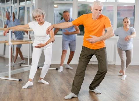 Elderly man ballet dancer executing ballet movements with group of older men and Stock Photos