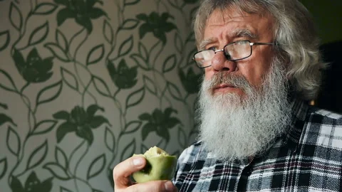 An elderly man with a beard in glasses bites an Apple. Healthy diet Stock Footage 86117947
