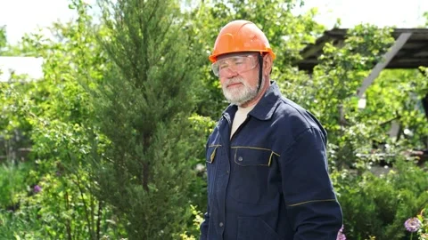 Elderly man with beard in hardhat and glasses with reciprocating saber saw. Stock Footage 130955274