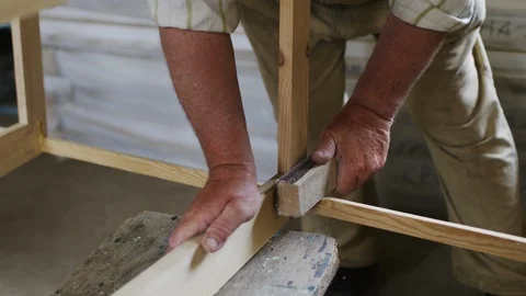 Elderly man carpenter builds a small boat with his hands out of wood in a small Stock-Footage 89786575