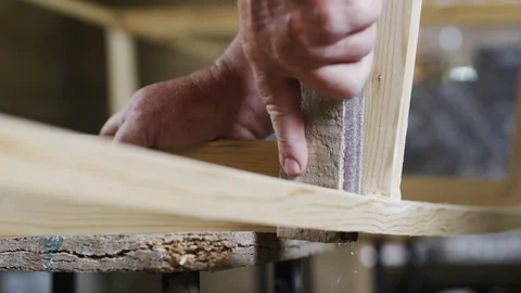 Elderly man carpenter builds a small boat with his hands out of wood in a small Stockbeeldmateriaal 89787417