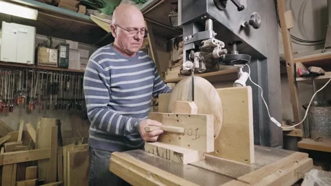 An elderly man in a carpentry workshop saws off the remains of a wooden Stock Footage 199765422