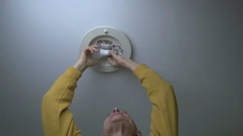 Elderly man changes light bulb in ceiling lamp and lights up in Stock Footage 221779592