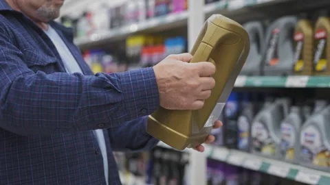 An elderly man chooses engine oil at an auto shop. Close-up of the hand Stock Footage 250197231