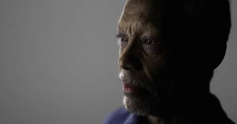 Elderly man with contemplative expression in minimal lighting setting Illustrazione stock