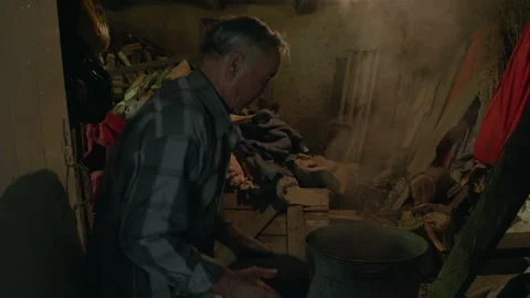 Elderly man cooking in a poor rustic home kitchen Stock Footage 331797869