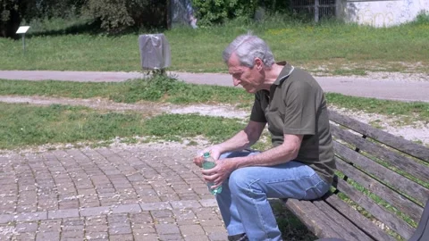 Elderly man cooling forehead with water bottle in summer heat Stock Footage 333194797