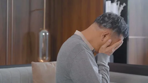 Elderly man crying lonely after talking on mobile phone, sits indoors in living Stock Footage 334307399