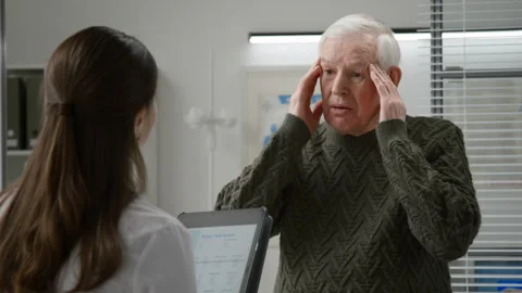 Elderly Man Describing Headache to Young Female Doctor in Exam Room Stock Footage 333204133