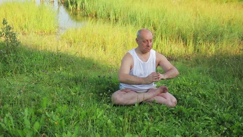 An elderly man does exercises on his feet on the lake in the morning Stock Footage 114509059