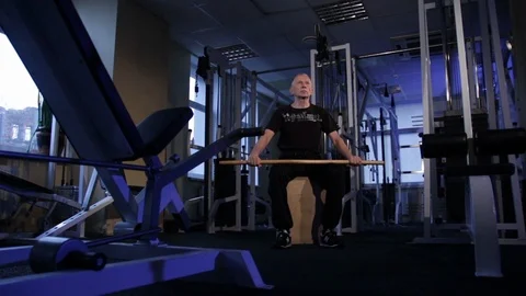 An elderly man does an isometric exercise with a stick, holding it over his head Stock Footage 115243957