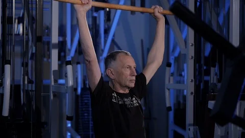 Elderly man does an isometric exercise with a stick, holding it behind the back Stock Footage 115847063
