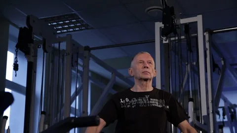 An elderly man does an isometric exercise with a stick, holding it over his head Stock Footage 115923898
