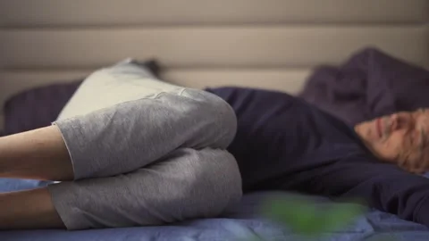 An elderly man does yoga exercises after waking up on his bed Stock Footage 293320784