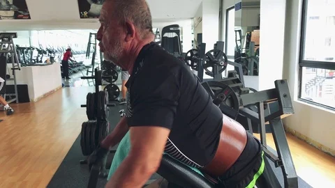 Elderly man doing back exercise at gym with weights Stock Footage 83183456