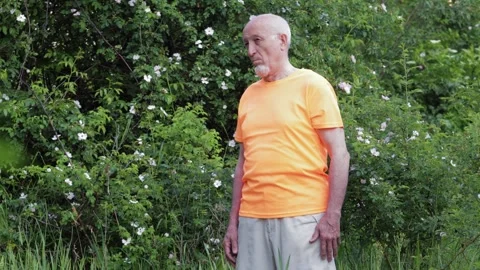 An elderly man doing exercises against a backdrop of nature Stock Footage 310890572