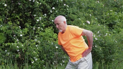 An elderly man doing exercises against a natural backdrop Stock Footage 310890706