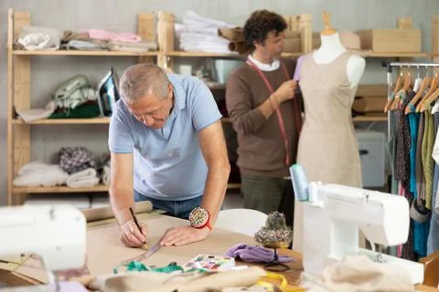 Elderly man drawing pattern on paper male assistant sews on mannequin Stock Photos