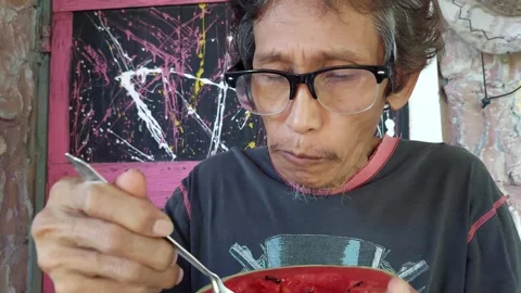 An elderly man eats a very red and delicious Stock Footage 257578393