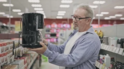 An elderly man in an electronics hypermarket chooses a coffee maker. A pensioner Stock Footage 251735038
