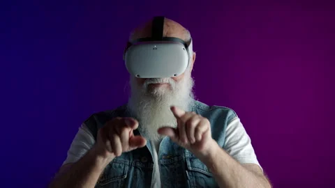 Elderly Man Engaging in Virtual Reality on Colorful Background Stock Footage 262489760