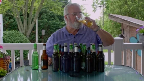 Elderly Man Enjoys Refreshing Drinks at a Backyard Table Full of Empty and .. Stock Footage 313946234