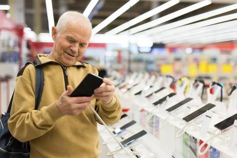 Elderly man examines tablet computer in showroom of electronics store Stock-Fotos