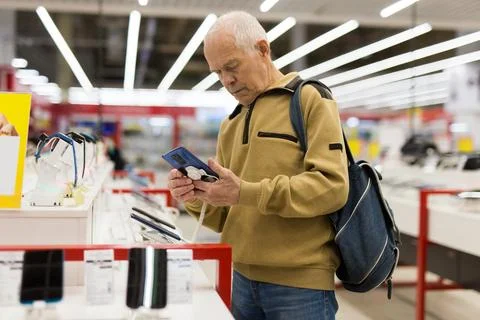 Elderly man examines tablet computer in showroom of electronics store Foto stock