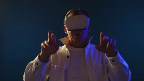 Elderly Man Explores Virtual World in VR Glasses, Interacts in Blue Room Stock Footage 263152334