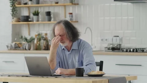 Elderly man feeling tired while touching his eyes with fingers feeling pain and Stock Footage 239837430