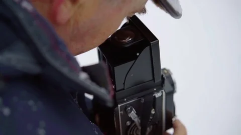 Elderly man is filming by old video camera, looking into lens and rotating Vidéo 102227310