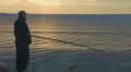 Elderly man fishing with rod from a rocky ocean shore, active rest, magic hour HD Footage