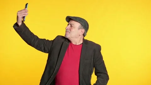 Elderly man with a flat cap taking a selfie with his smartphone Stock Footage 328093310