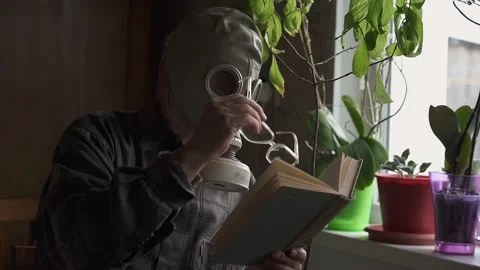 An elderly man in a gasmask in the hands of the glasses. reading a book Stock Footage 130523712