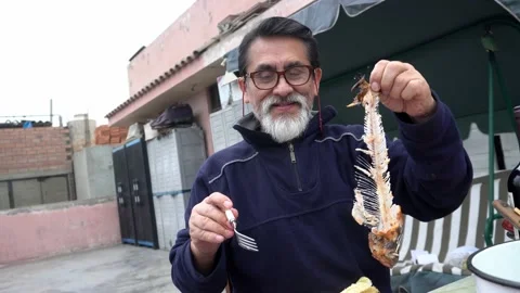 An elderly man with glasses holding a meatless trout fish with only bones proud 動画素材 160089901