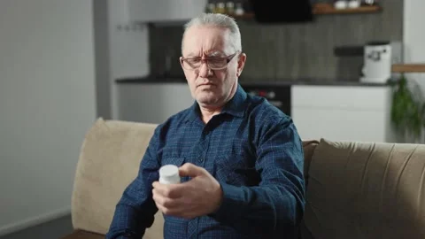 An elderly man with glasses trying to read the fine print on a drug package. A Stock Footage 234867880