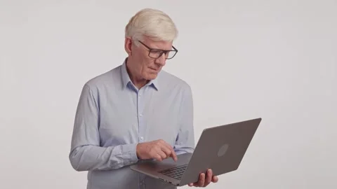 Elderly man with glasses using laptop as output device in office Stock Footage 266921801