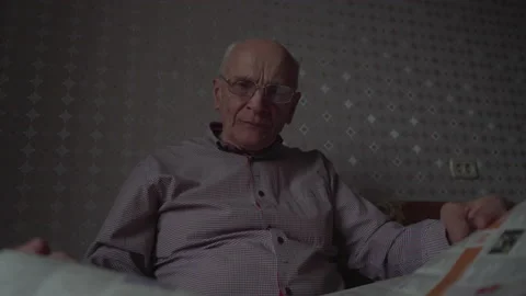 Elderly man in glasses for vision opens newspaper and reads Stock Footage 239755579