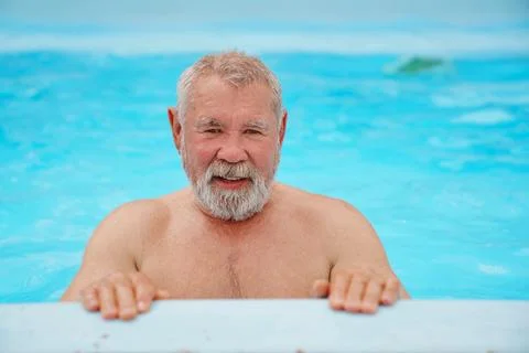 An elderly man with a gray beard in the pool. Stock Photos