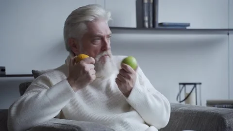 Elderly man with a gray beard sniffs lemon and Apple and does not smell Stock-Footage 142749529