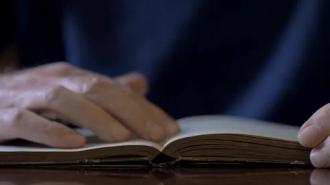 Elderly man hands flipping through pages of an old vintage book indoors Stock Footage 334776304