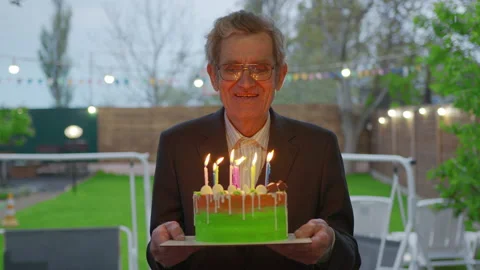 Elderly man holding a cake with burning candles. Stock Footage 130774926