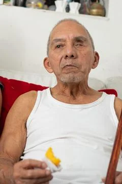 Elderly man holding empanada while sitting alone showing independence and d.. 库存照片