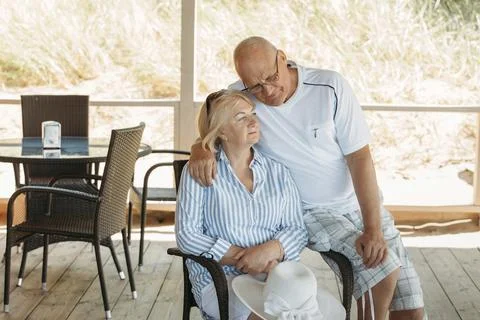 An elderly man hugs and talks to a woman on the terrace in a cafe. Stock Photos